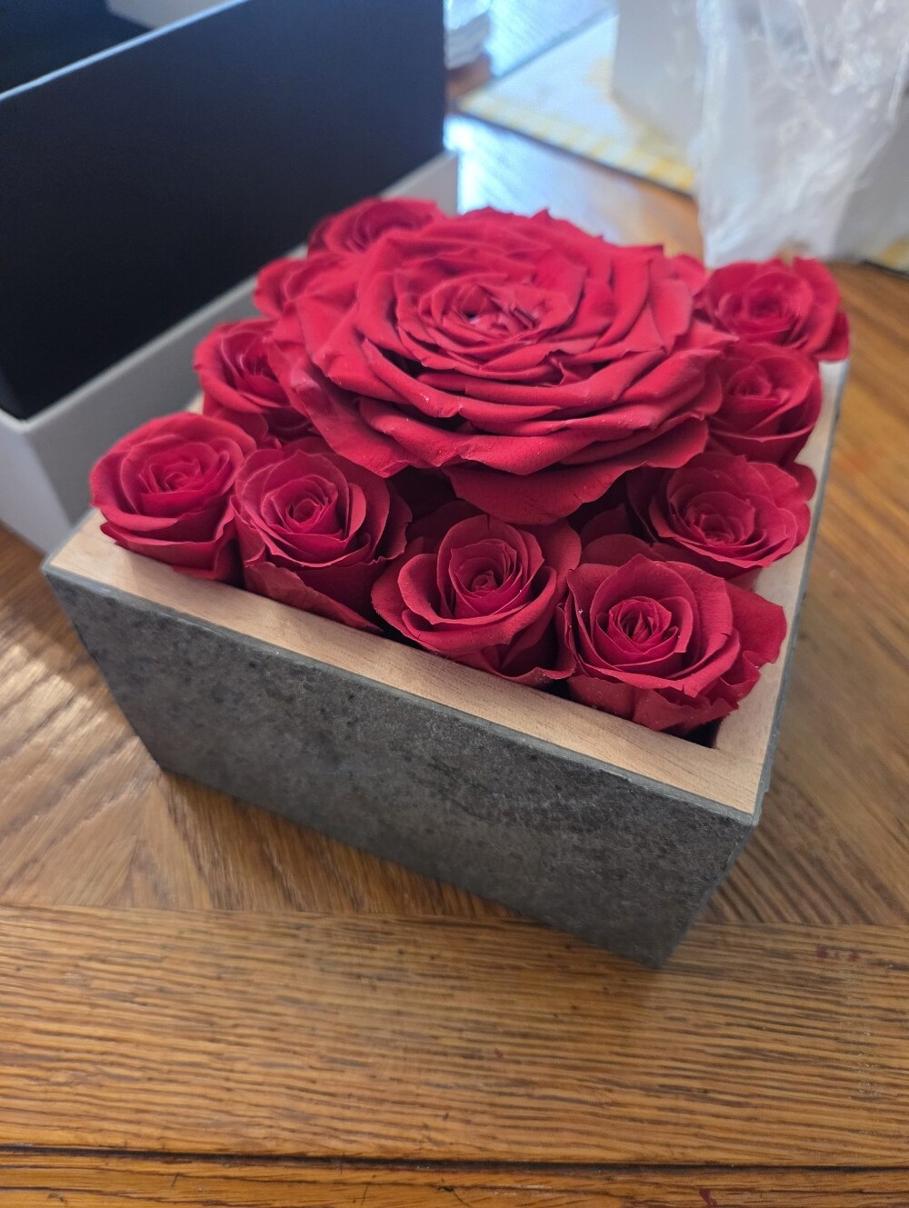 Preserved red rose arrangement presented in a textured gray rectangular box with